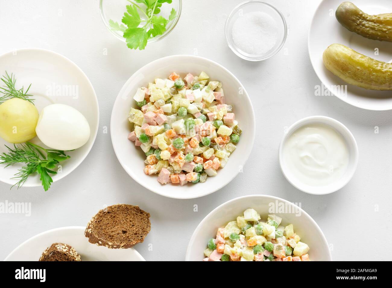 Olivier savoureux de salade de légumes bouillis et de la saucisse avec de la mayonnaise dans un bol. Nouvel An Russe ou salade de Noël sur fond noir en lumière. Haut de la vie Banque D'Images