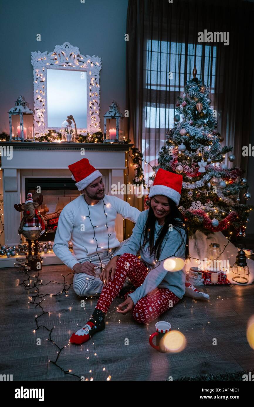 Cute couple arbre de Noël, couple drinking hot chocolate en vertu de  l'arbre de Noël par la cheminée dans le salon Photo Stock - Alamy