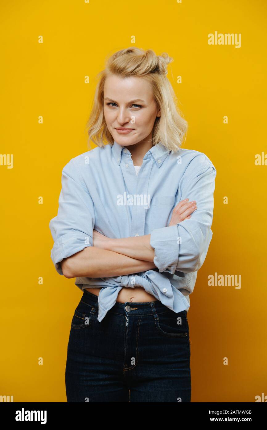 Portrait d'une jolie femme blonde avec des mains sur sa taille sur jaune Banque D'Images