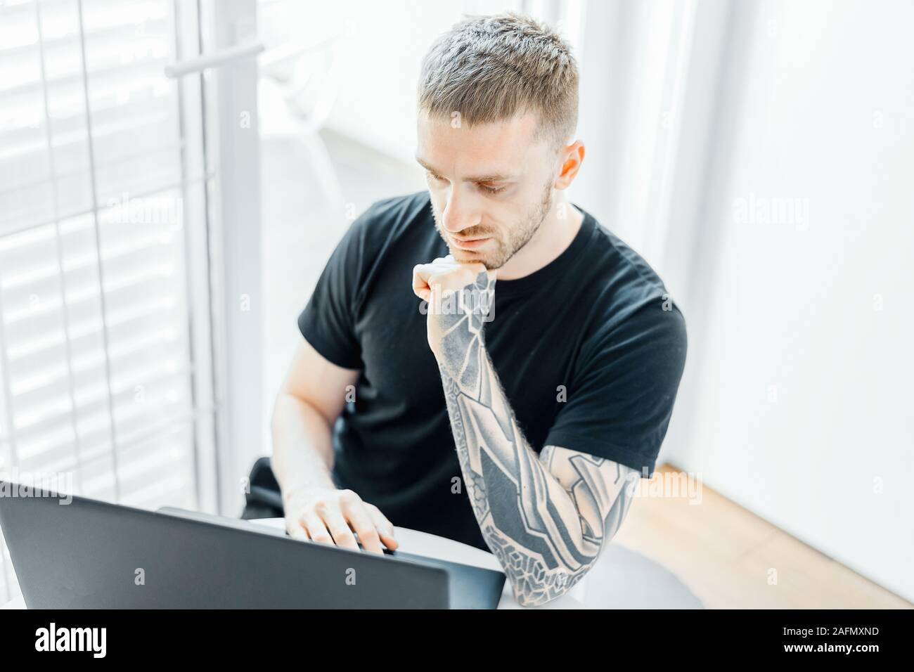 Handsome Smiling Man working on Laptop in Modern appartements lumineux. Travailleur indépendant qui travaille à la maison. Jeune Entrepreneur. Banque D'Images