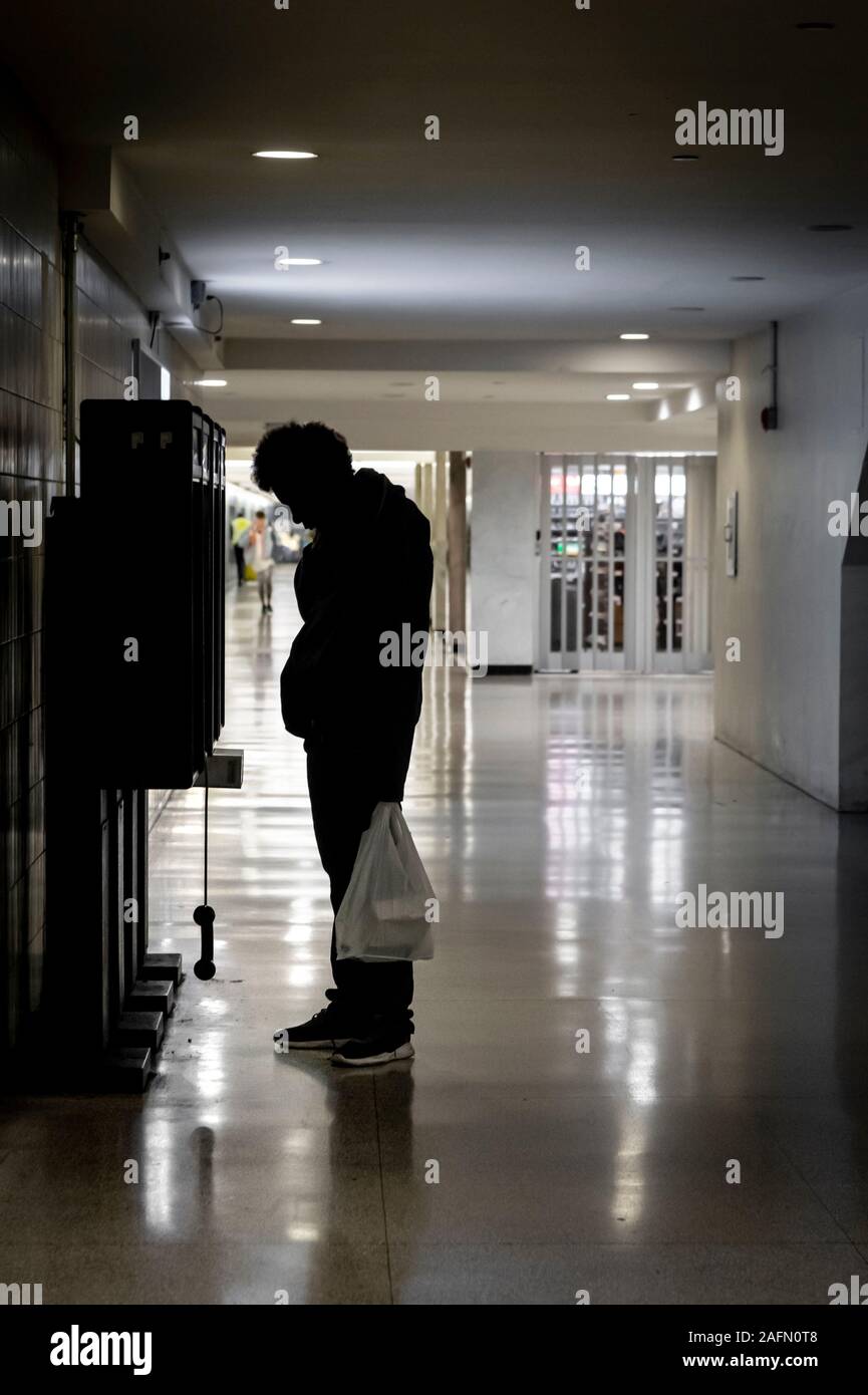 Un homme sans abri souffrant de troubles mentaux affamant au téléphone Banque D'Images
