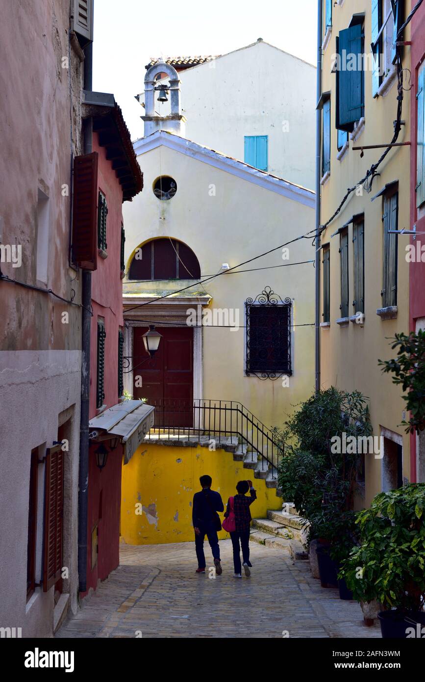 Deux personnes marchant le long de la petite rue pittoresque dans la ville historique de Rovinj, Croatie Banque D'Images