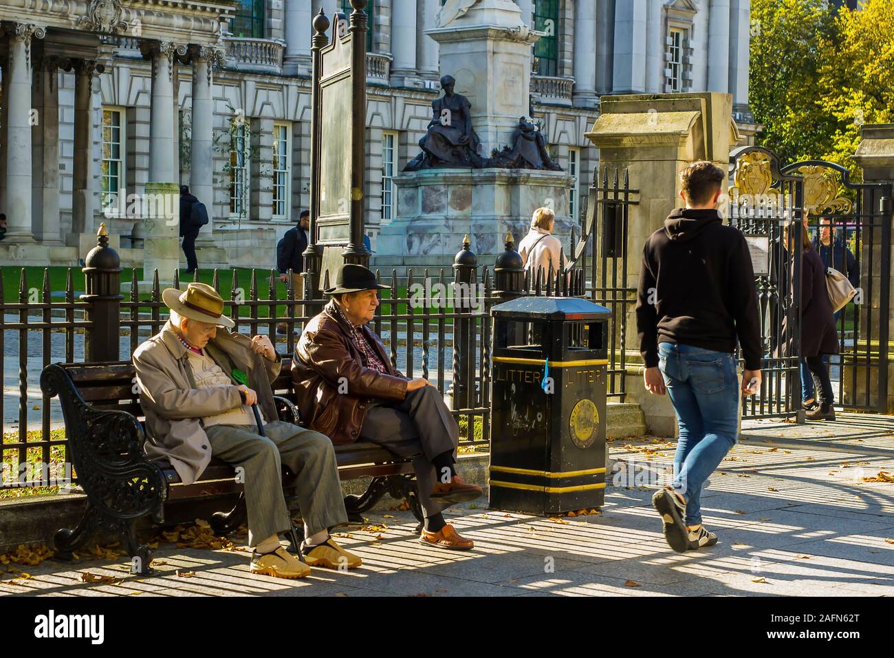 16 octobre 2019 une paire de vieux messieurs se reposant dans le sunshineat automne lumineux Belfast Irlande du Nord comme le monde les transmet par. Banque D'Images