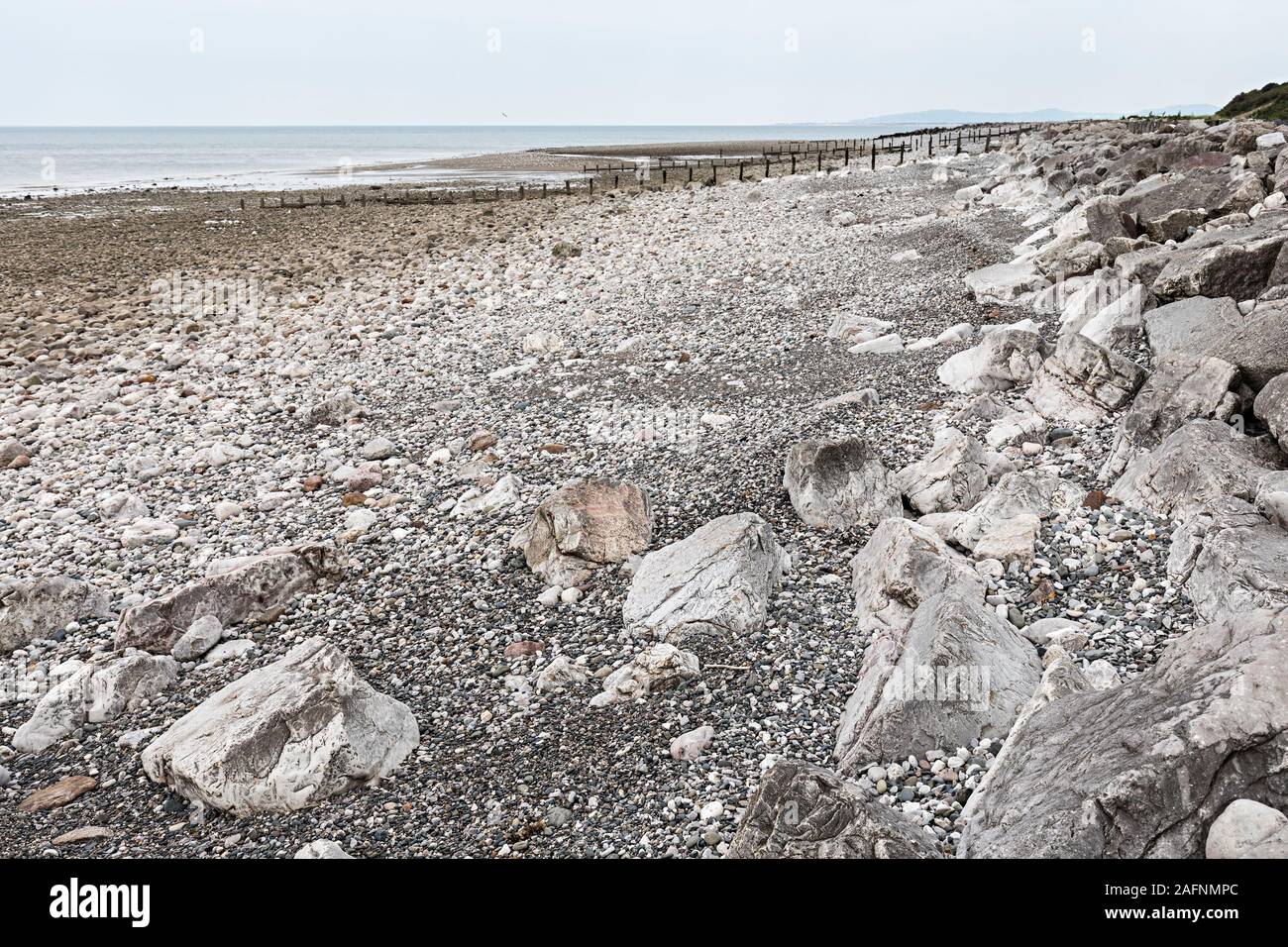 La plage pavée et pierres utilisées pour la protection contre l'érosion côtière, Llanddulas, Conwy, Pays de Galles, Royaume-Uni Banque D'Images