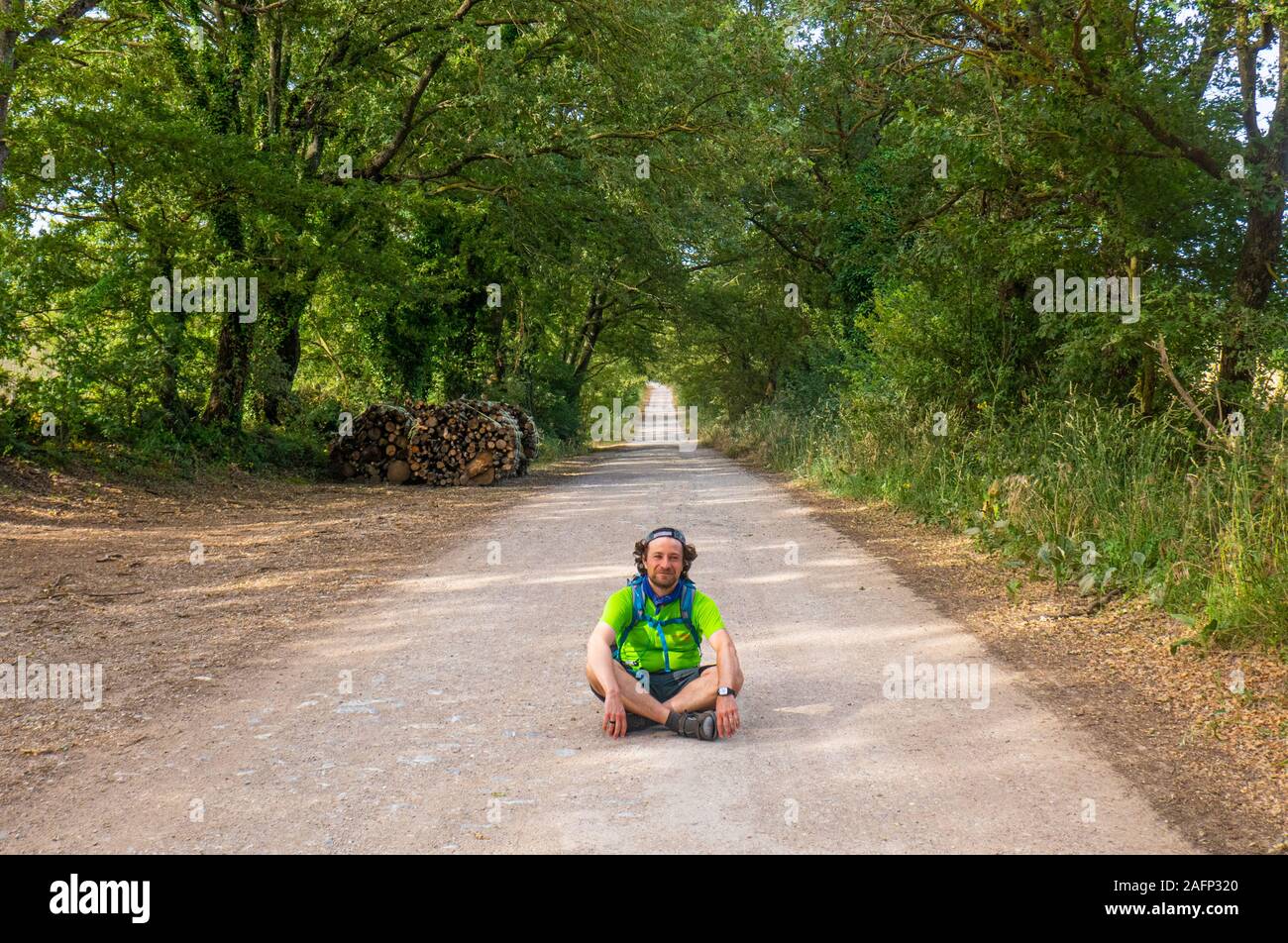 Un voyageur solitaire assis au centre de la route dans la campagne italienne Banque D'Images