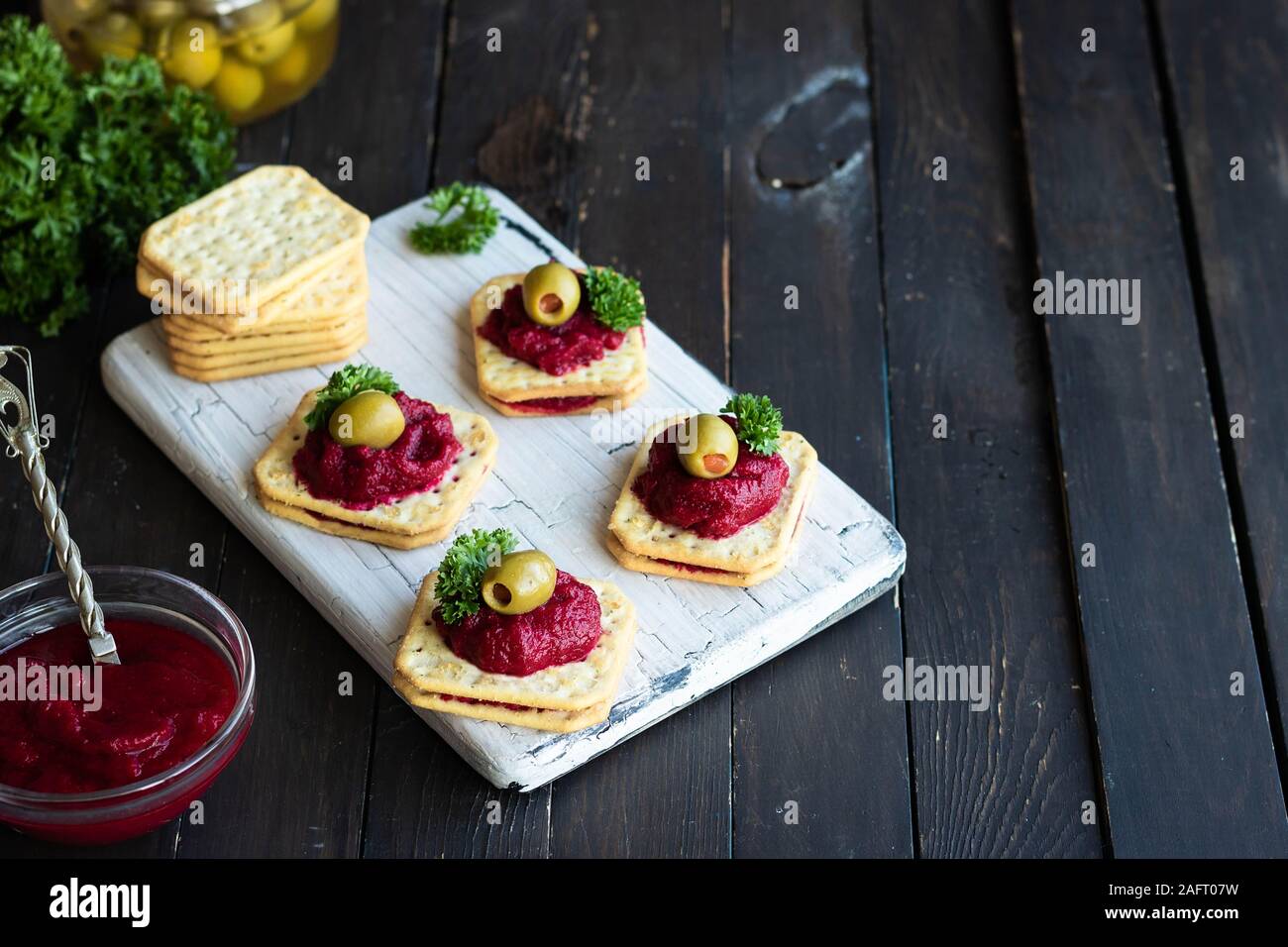 La relish de betteraves rouges aux olives farcies de poivron rouge sur des craquelins. Portionné original pour un apéritif au banquet ou. Banque D'Images