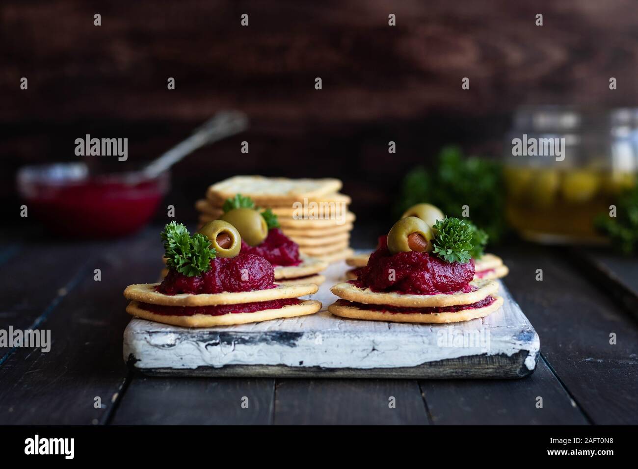 La relish de betteraves rouges aux olives farcies de poivron rouge sur des craquelins. Portionné original pour un apéritif au banquet ou. Banque D'Images