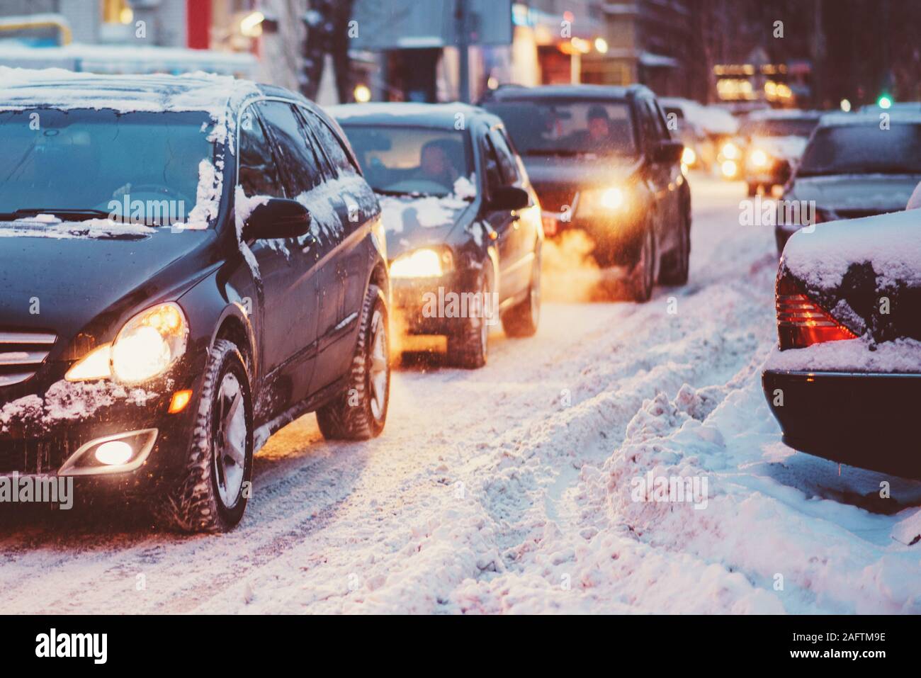 Automobiles sur une route enneigée dans la soirée en Russie Banque D'Images