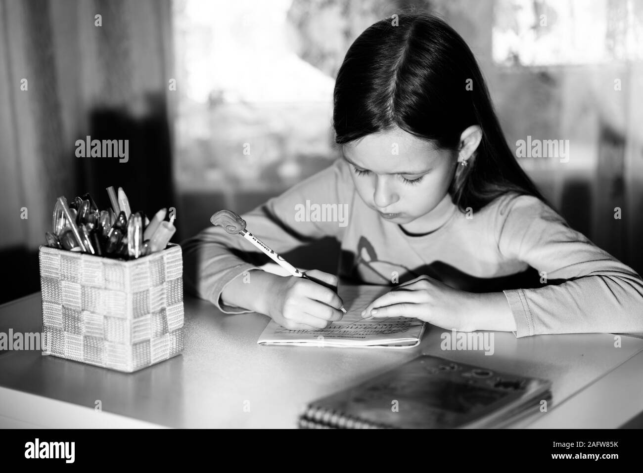 Petite fille assise à la table à faire leurs devoirs Banque D'Images