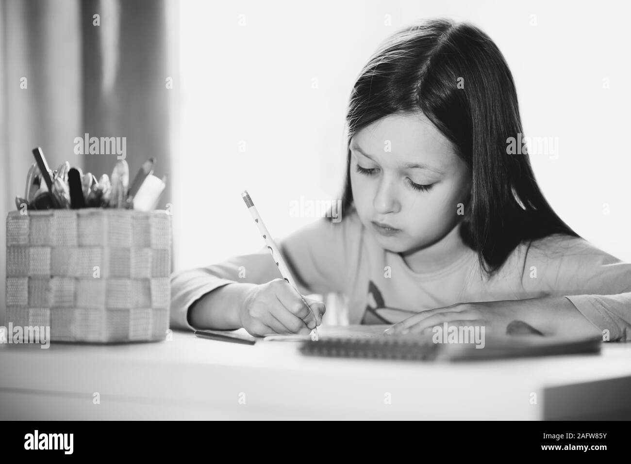 Petite fille assise à la table à faire leurs devoirs Banque D'Images