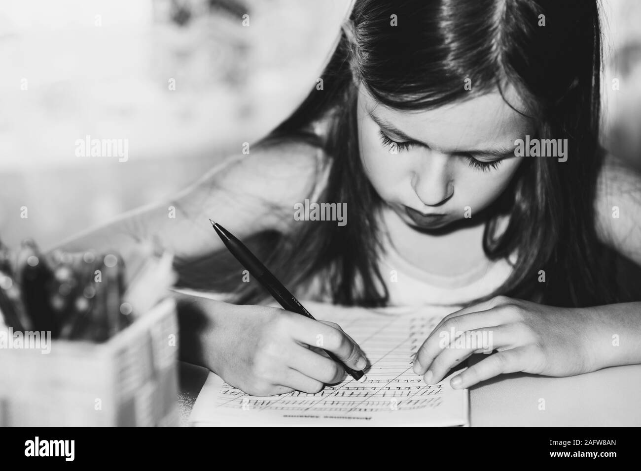 Petite fille assise à la table à faire leurs devoirs Banque D'Images