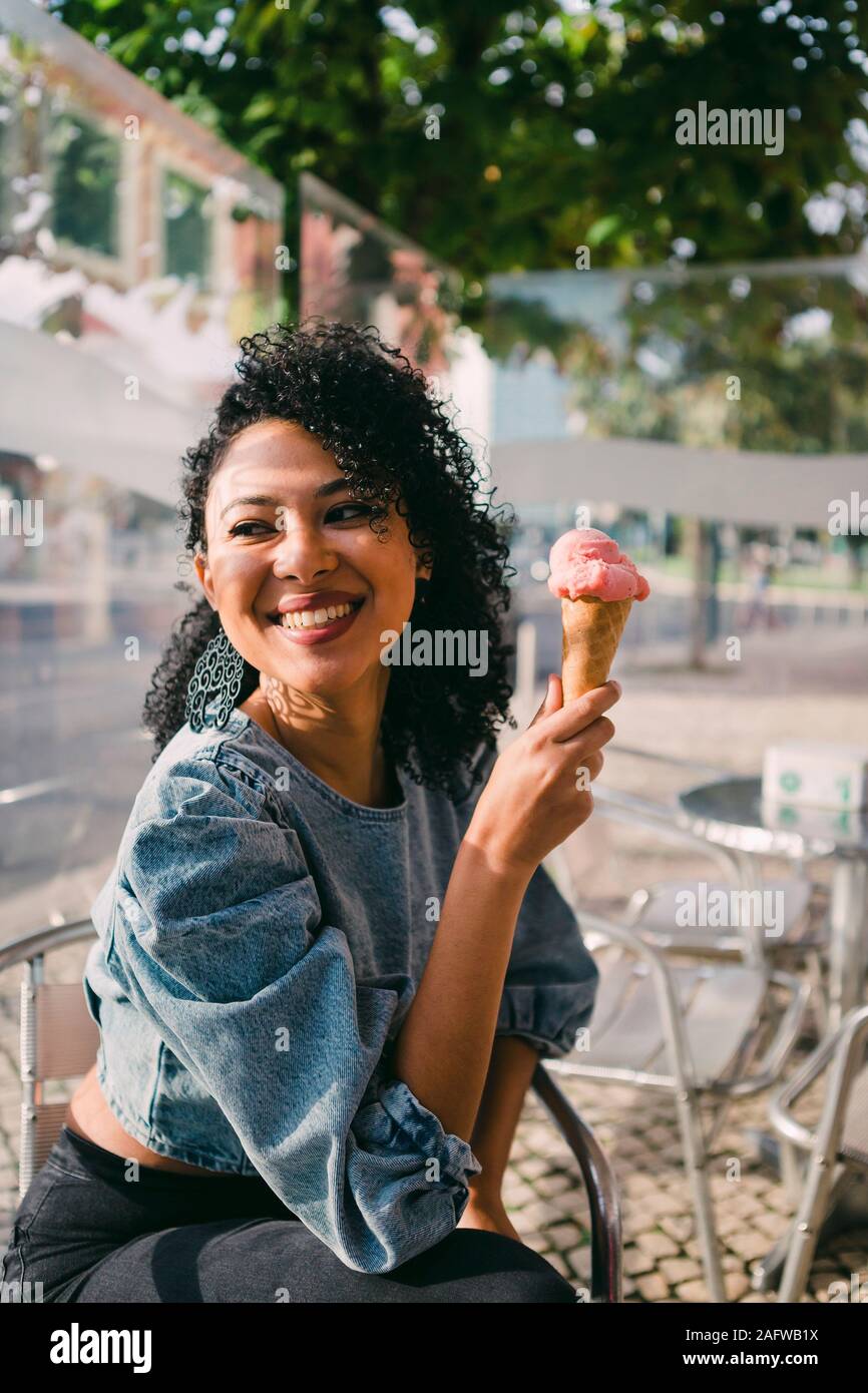 Happy woman eating ice cream cone sur sunny patio cafe Banque D'Images