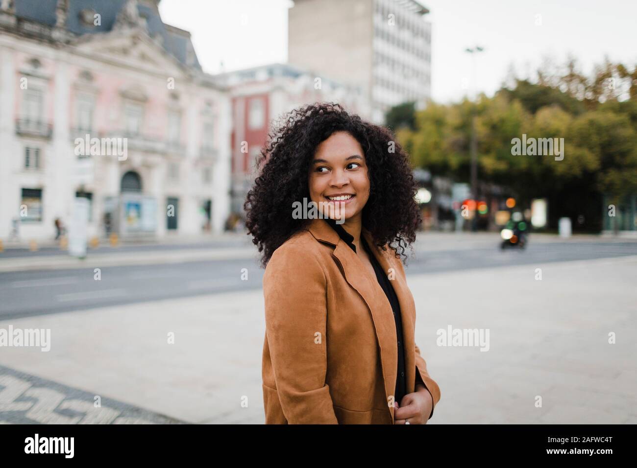 Happy young woman looking over Shoulder on urban street Banque D'Images