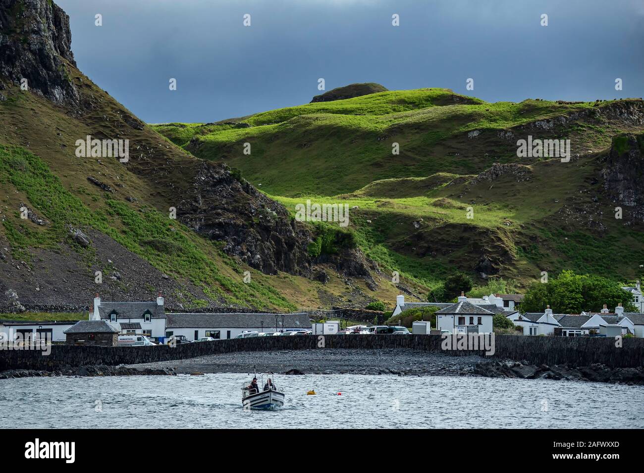 Regarder en arrière vers le port de Ellenabeich, un petit village sur l'île de seil d'Easdale Island, avec le petit bateau s'approcher. Banque D'Images