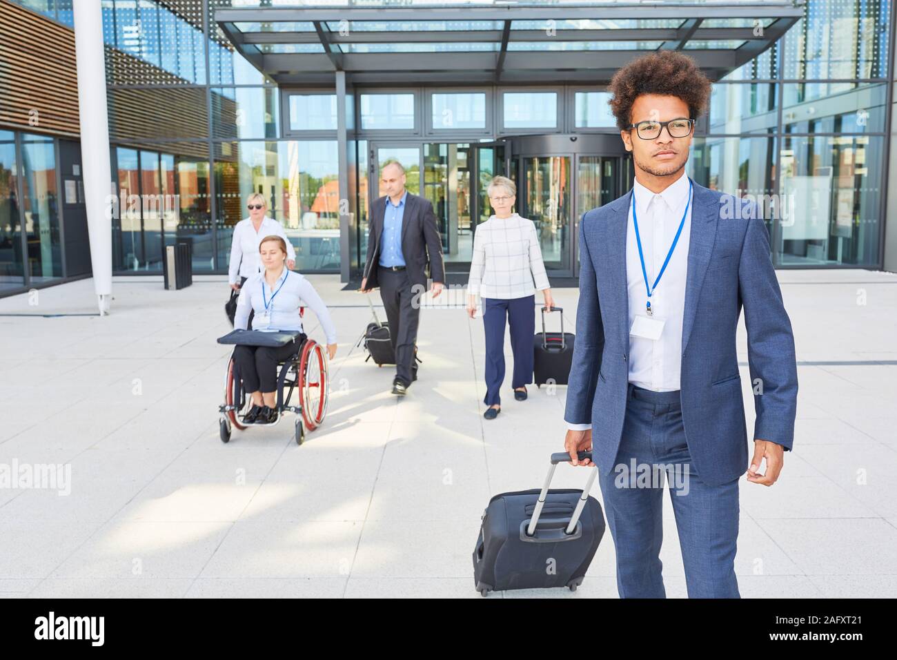Groupe de gens d'affaires avec des valises en voyage d'affaires avec un collègue en fauteuil roulant Banque D'Images