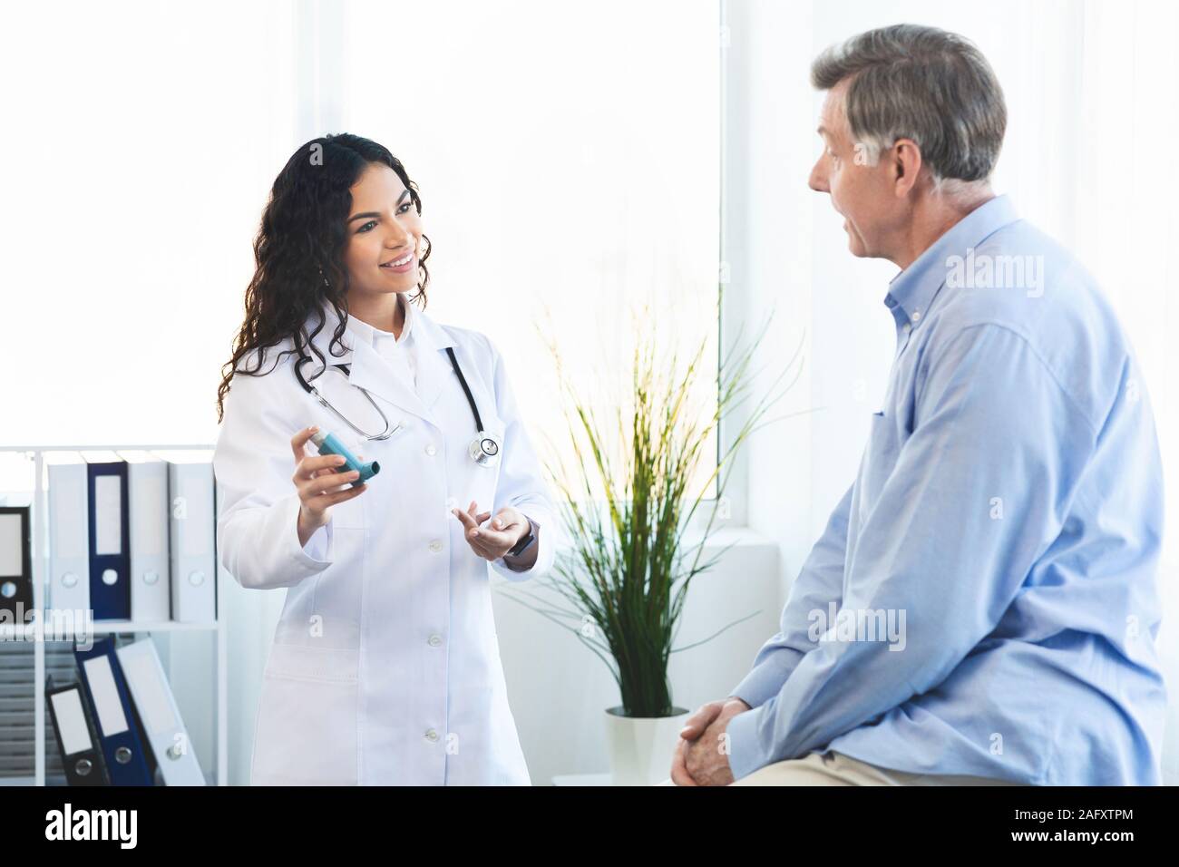 Médecin montrant un homme âgé asthme inhalateur bleu Banque D'Images