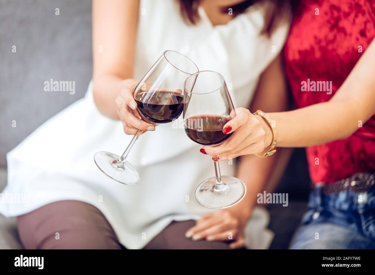 Les personnes qui boivent du vin rouge part clink verres ensemble dans la partie. Banque D'Images