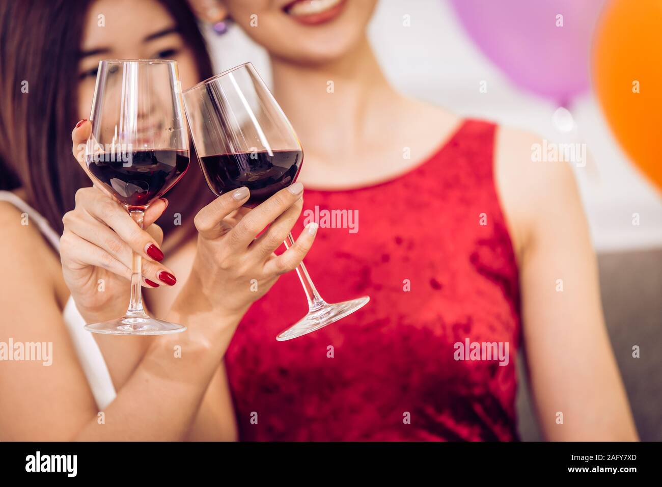 Deux femmes asiatiques drinking red wine part clink verres ensemble dans la partie. Banque D'Images