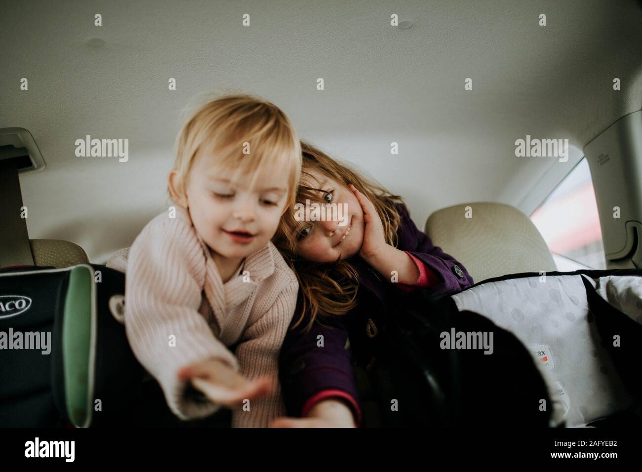Les soeurs se penchant sur le siège arrière de voiture accompagné Banque D'Images
