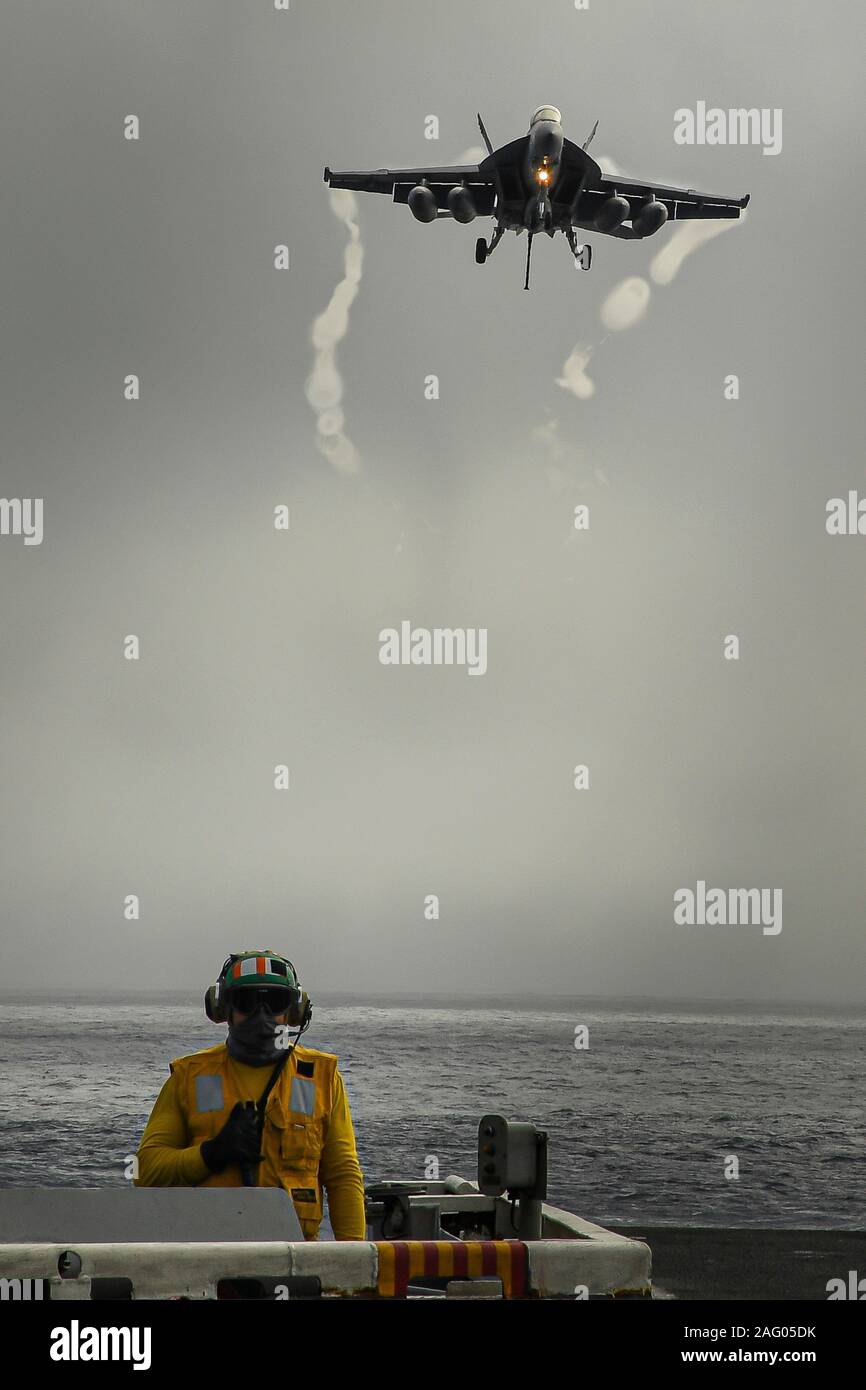 Un U.S. Navy F/A-18F Super Hornet jointe à la grève de Tomcatters escadron de chasse 154 approches, le poste de pilotage de la classe Nimitz porte-avions USS Theodore Roosevelt à l'atterrissage sur un jour de pluie au large de la côte de Californie le 13 décembre 2019 dans l'océan Pacifique. Banque D'Images
