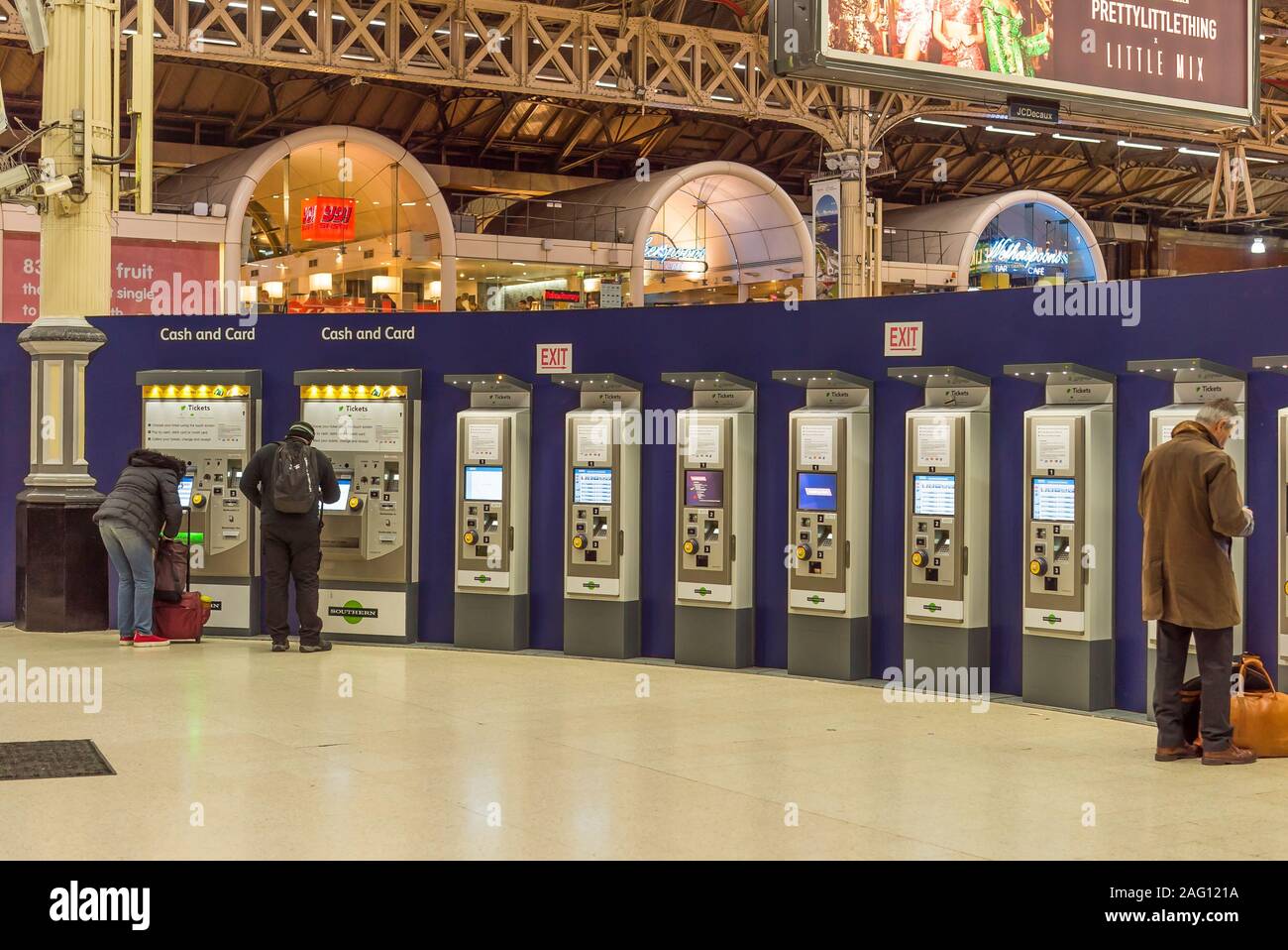 Passagers à l'intérieur de la gare Victoria de Londres, Royaume-Uni (Londres, deuxième poste station), comité permanent des distributeurs de billets automatiques à l'achat de billets de train de nuit. Banque D'Images