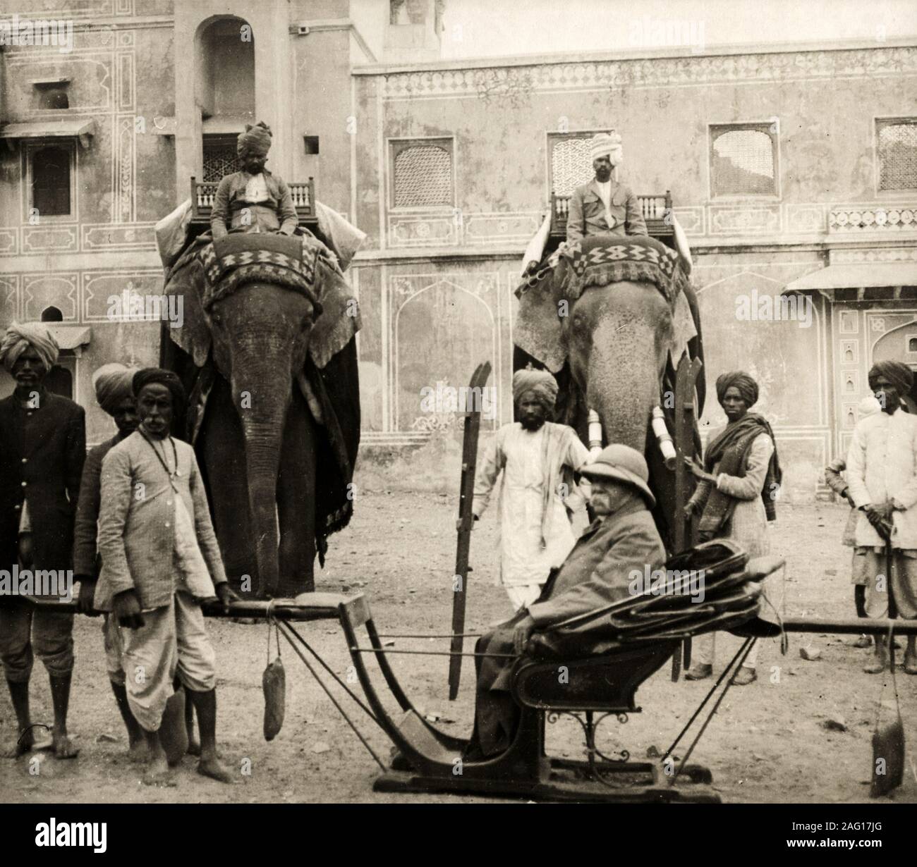 Au début du xxe siècle vintage photographie de presse - les éléphants de cérémonie avec howdah et mahout, avec un européen dans un fauteuil et porteurs Banque D'Images
