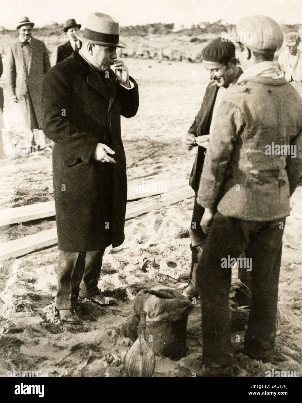 Au début du xxe siècle - photographie vintage press leader fasciste italien Benito Mussolini mangé des moules tout en visitant les pêcheurs de Ostia, Rome, c.1920s Banque D'Images