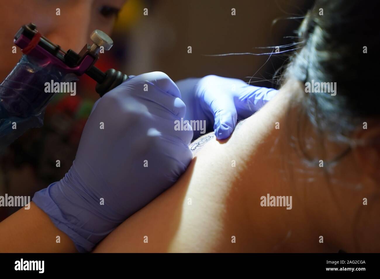 Middletown, CT / USA - 7 décembre 2019 : artiste de tatouage se concentre en traçant un dessin de tatouage floral sur l'arrière du cou du client Banque D'Images