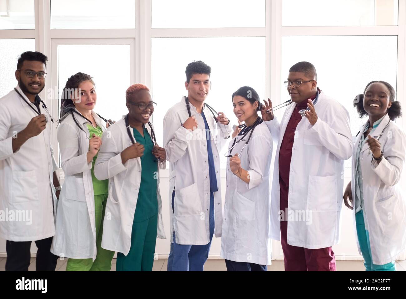 Les étudiants en médecine, médecins, race mixte. Une équipe de jeunes gens en blouse blanche posant dans le couloir de l'hôpital Banque D'Images