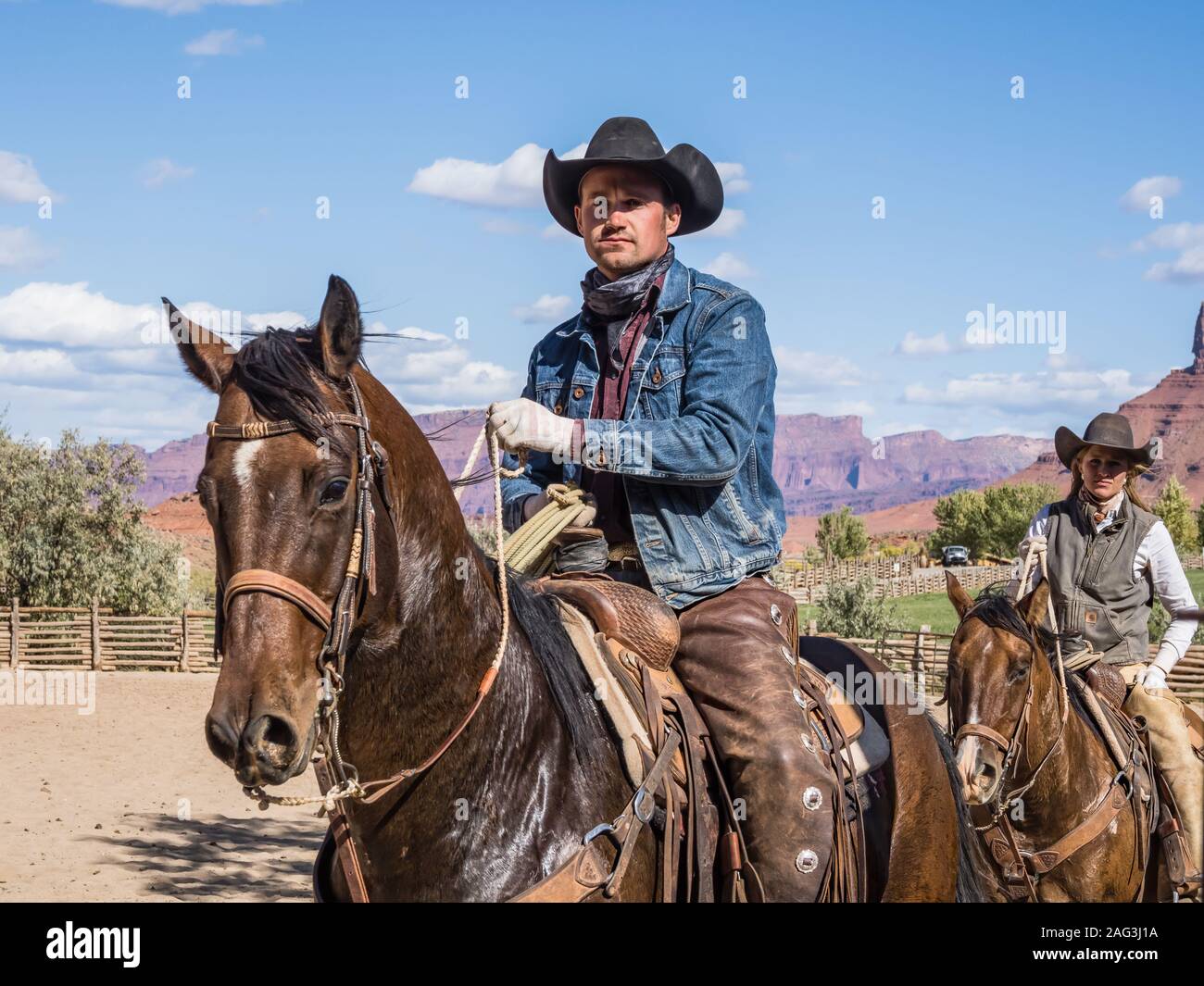 Un groupe de cowboy et cowgirl wrangler sur un ranch près de Moab, Utah. Derrière sont les falaises de grès du canyon de la rivière Colorado. Banque D'Images