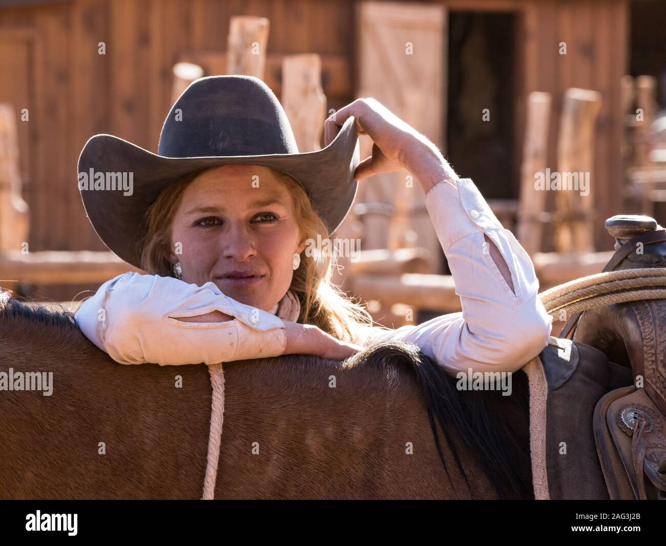 Un jeune groupe de travail attrayant wrangler cowgirl pose avec son cheval dans un ranch près de Moab, Utah. Banque D'Images