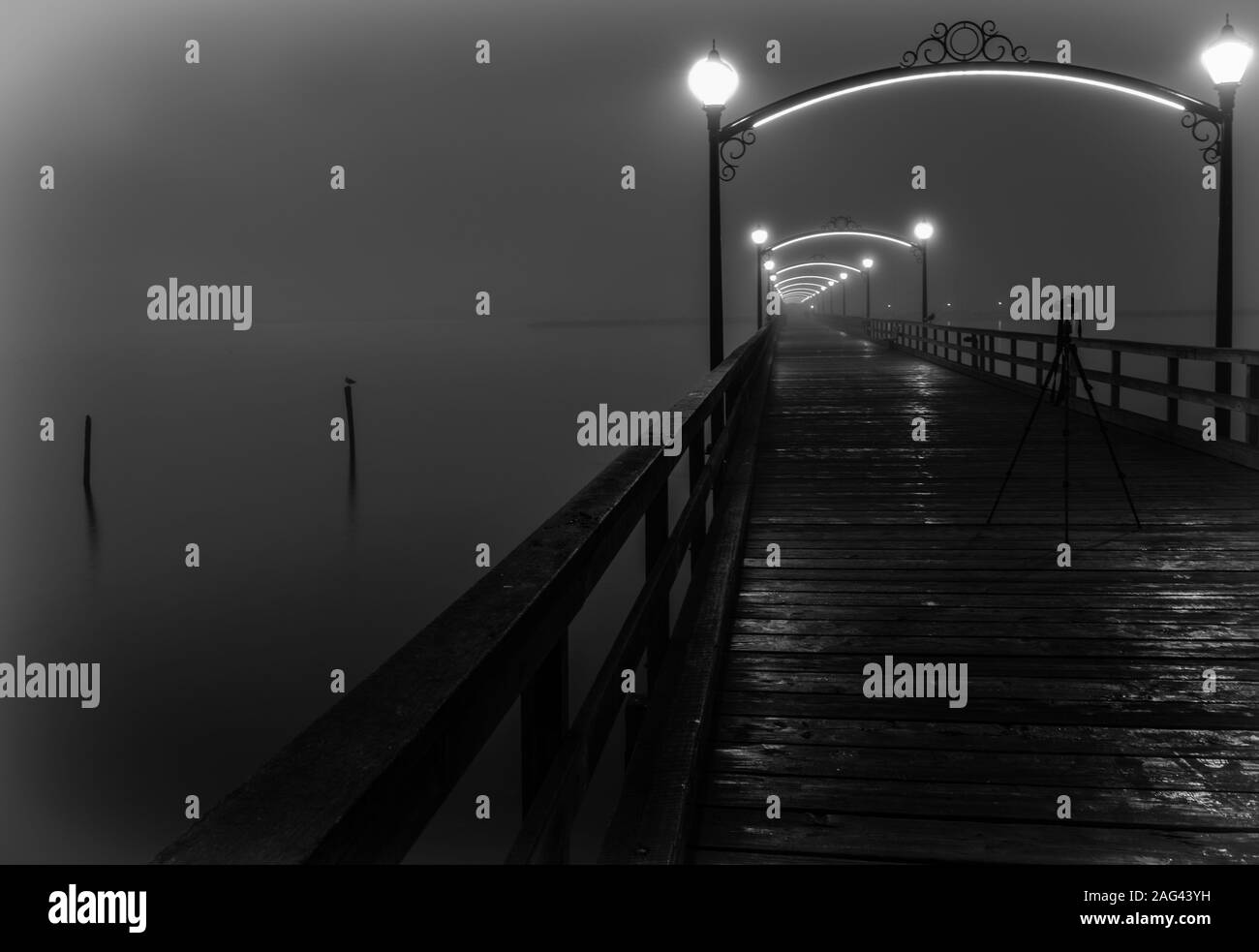 Un support de caméra au milieu d'un pont en bois avec lanternes éclairées enveloppées de brouillard Banque D'Images