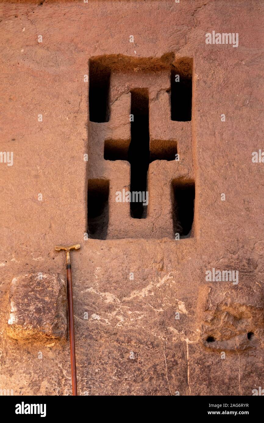 L'Éthiopie, l'Amhara, Lalibela, anciennes églises, Bet Medhane Alem, église cruciforme sculpté fenêtre avec prière traditionnelle stick appuyé contre Banque D'Images