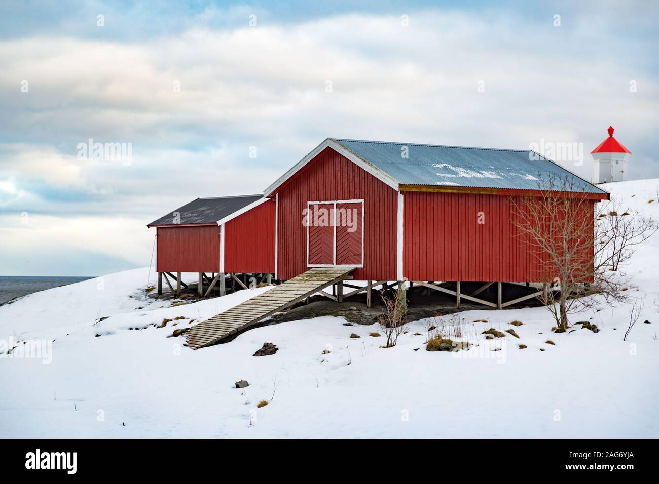 Rorbuer rouge maisons et phare à îles Lofoten, Norvège. Paysage de neige Banque D'Images