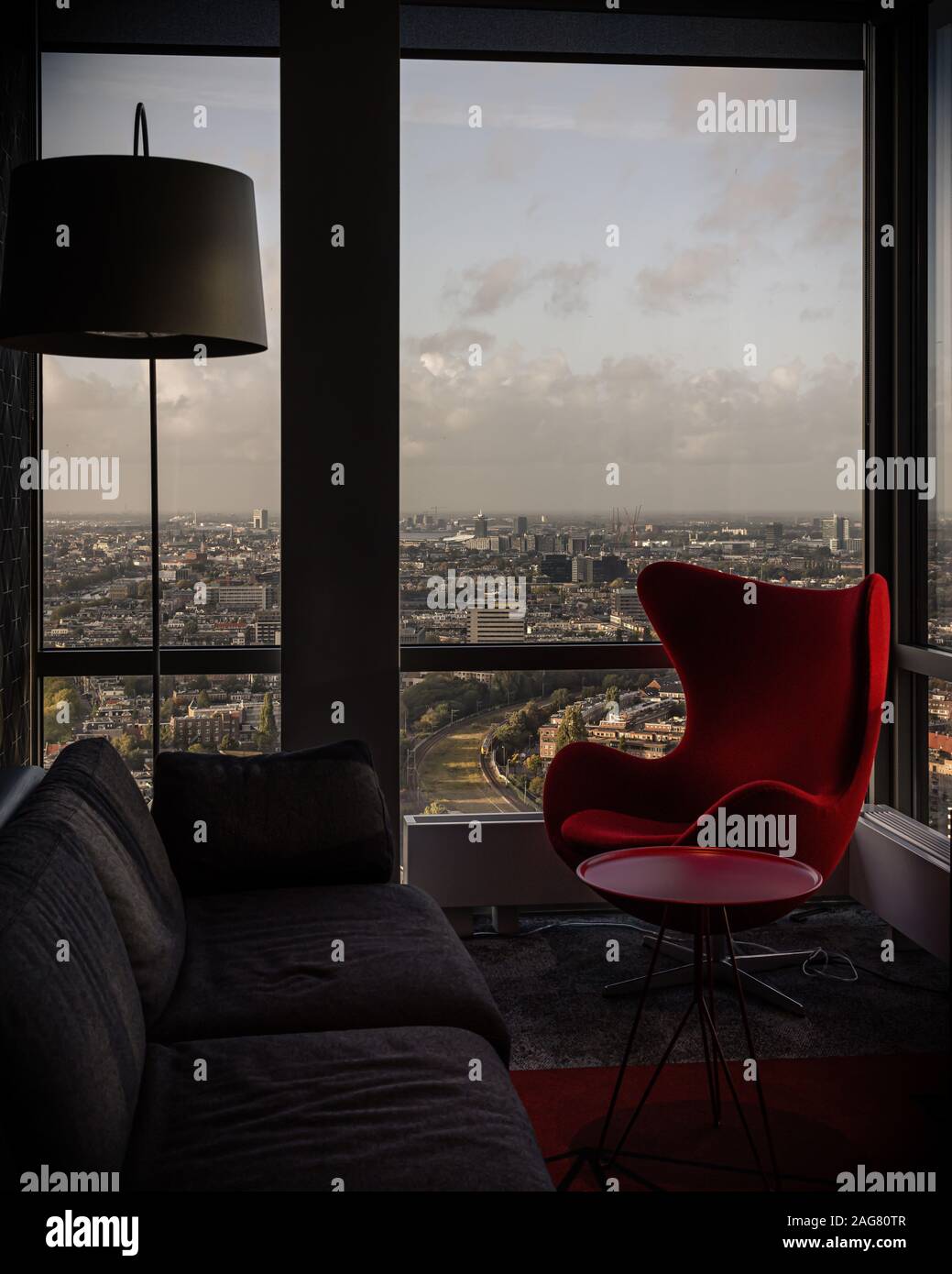 Vue verticale d'un fauteuil rouge à côté de la fenêtre d'un appartement à un étage élevé Banque D'Images