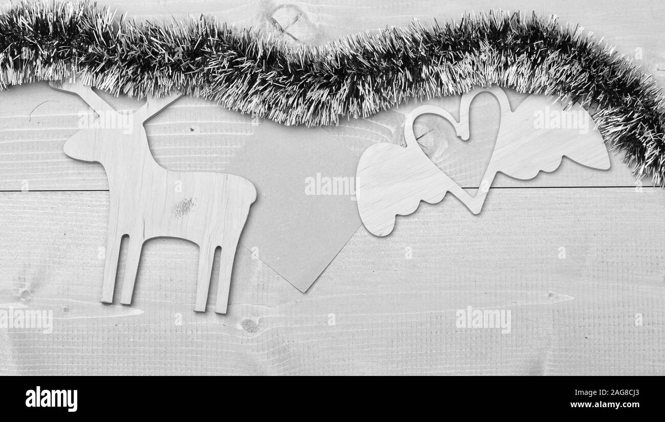Les guirlandes avec des ornements de Noël et le papier blanc note de fond en bois. Joyeux noël concept. Ornements de Noël en bois et le cerf et coeur toy vert scintillant scintillants. Ornements de Noël. Banque D'Images