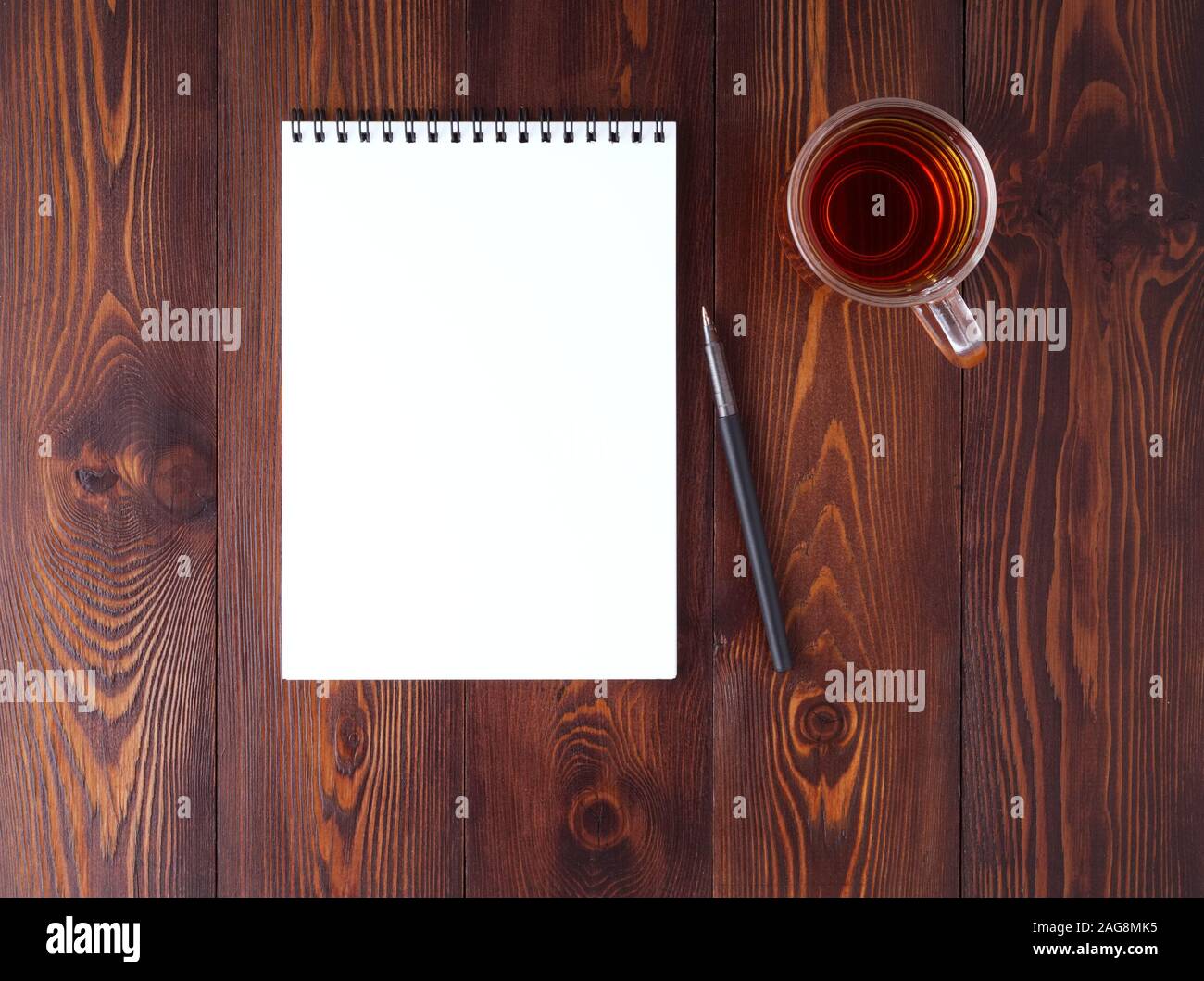 L'ouvrir le bloc-notes avec crayon , spirale, tasse de thé sur une table en bois brun foncé, vue du dessus Banque D'Images