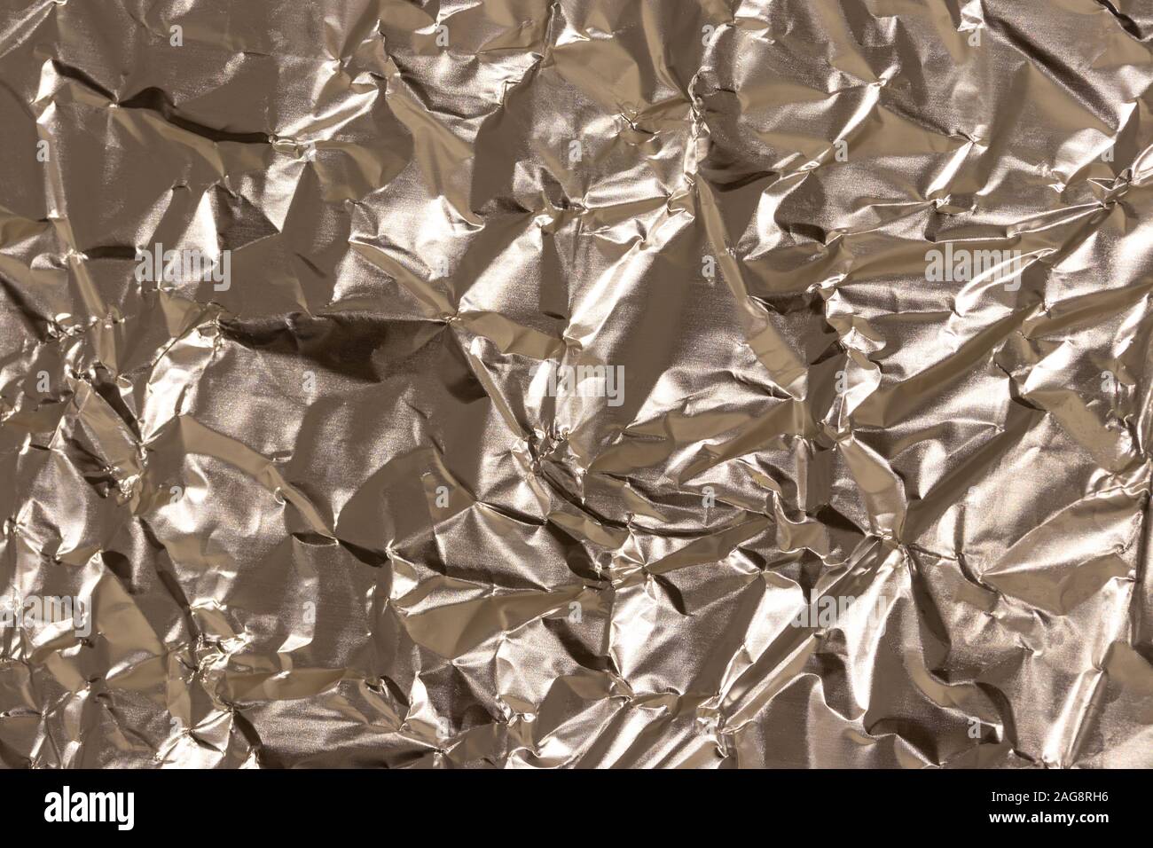 La texture du papier aluminium froissé cuisine d'or. Résumé en blanc pour la conception. Banque D'Images