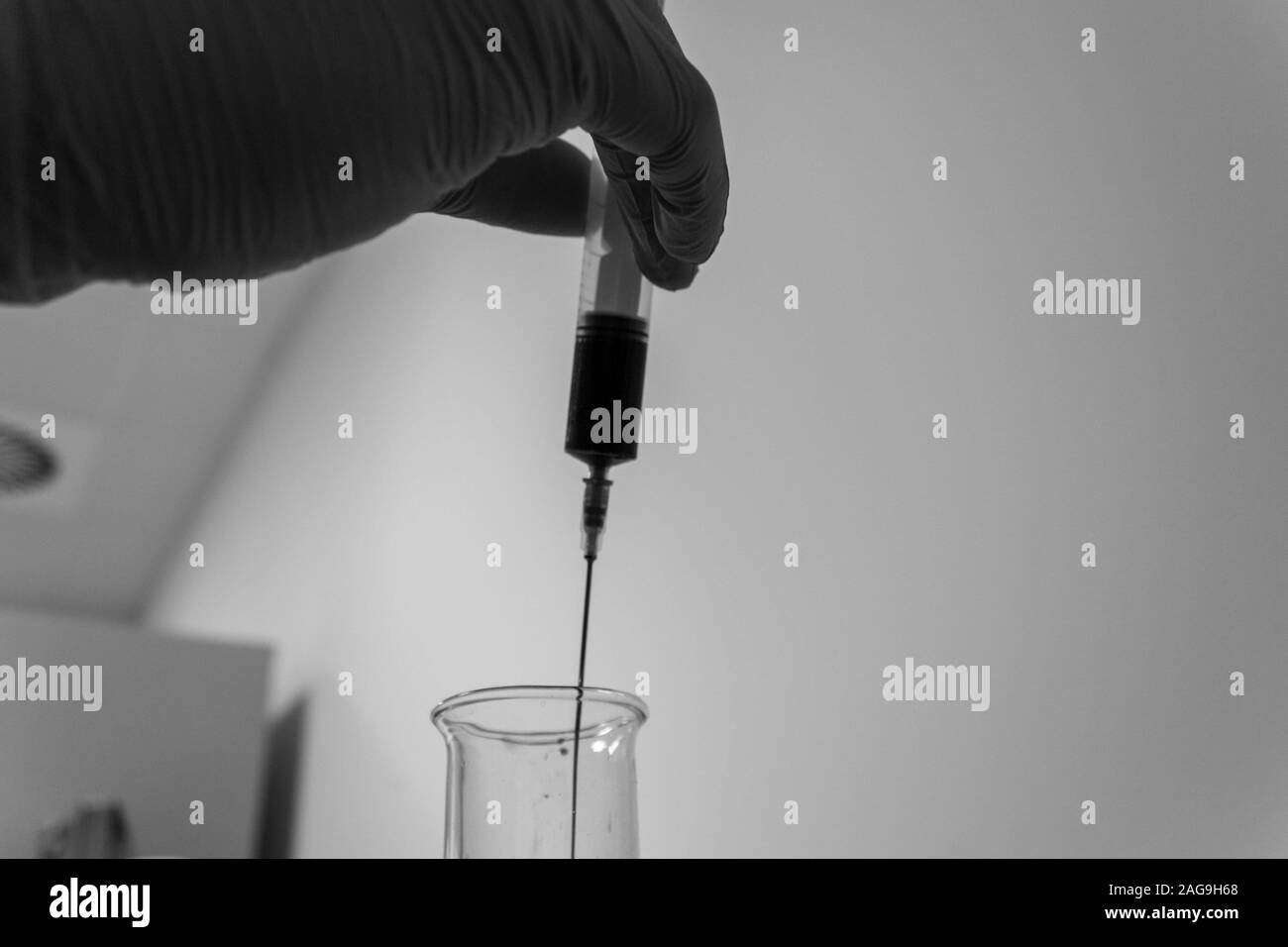 Prise de vue en niveaux de gris un assistant de bibliothèque faisant des expériences avec une pipette et un tube à essai Banque D'Images