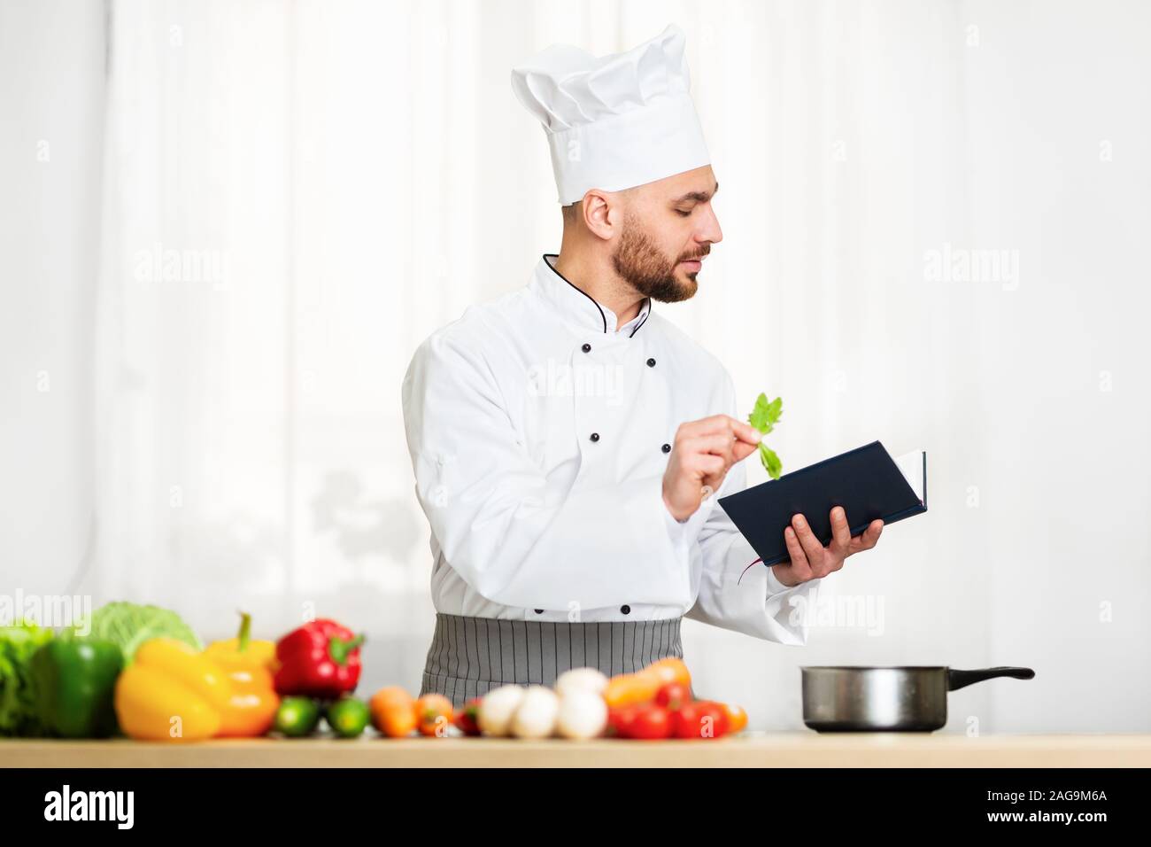 La lecture de l'homme chef de livre de recettes de cuisine à préparer le dîner dans la cuisine Banque D'Images