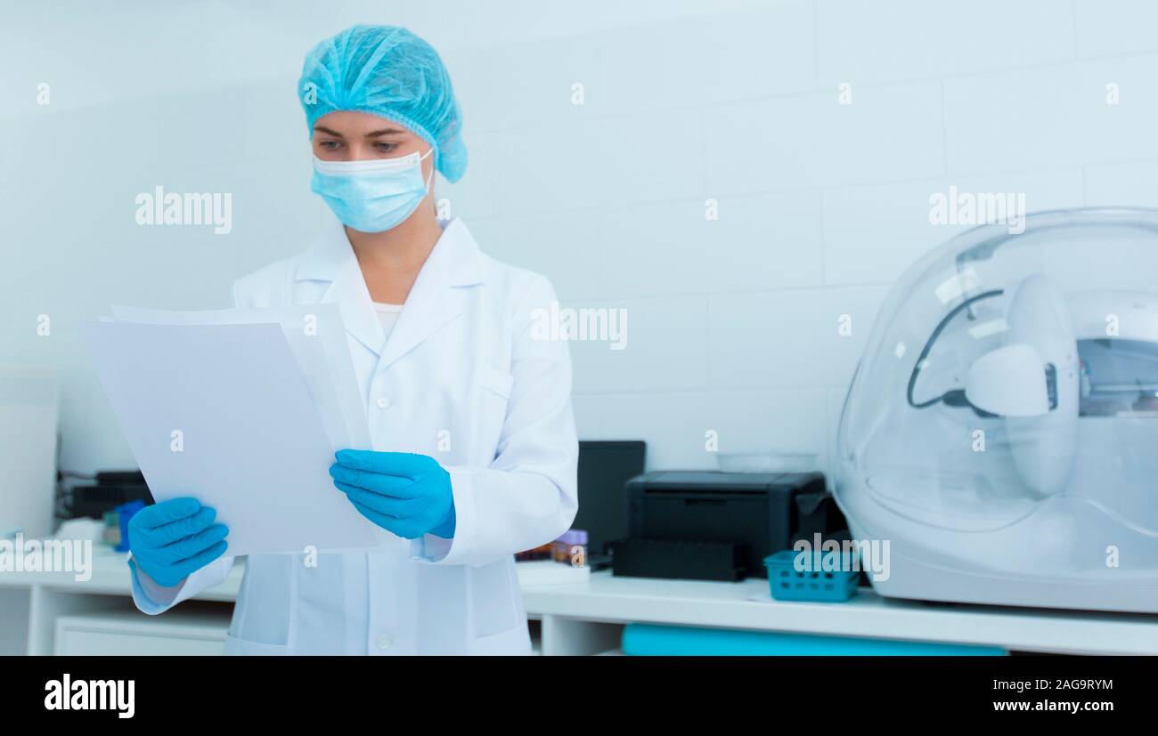 Cheerful woman en masque de protection et des gants de la lecture des résultats de l'analyse Banque D'Images