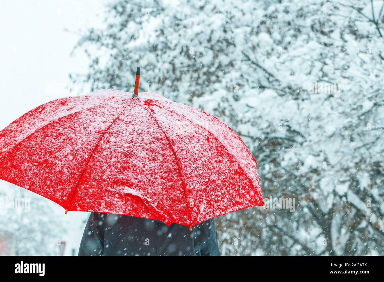 Femme sous parapluie rouge dans la neige profiter de la première neige de la saison d'hiver Banque D'Images