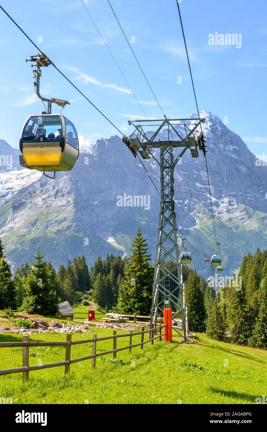 Câble jaune voiture dans les Alpes suisses. Gondola allant de Grindelwald en premier dans la région de la Jungfrau. Paysage alpin d'été avec des montagnes aux sommets enneigés en arrière-plan. Transport de touristes. Banque D'Images