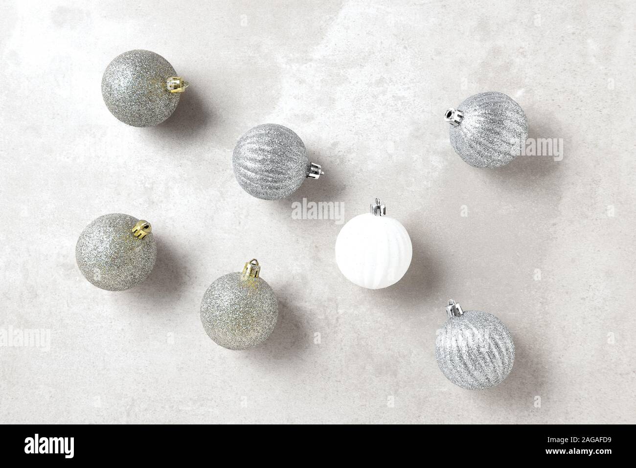 L'argent et l'or des ornements de Noël avec une seule boule blanche, format horizontal sur un gris clair table. Banque D'Images