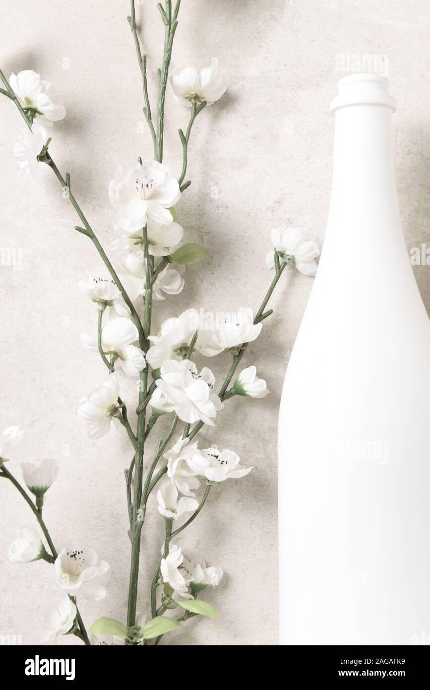 Mise à plat et bouteille de champagne blanc des fleurs sur un gris clair tacheté de table. Format vertical. Banque D'Images