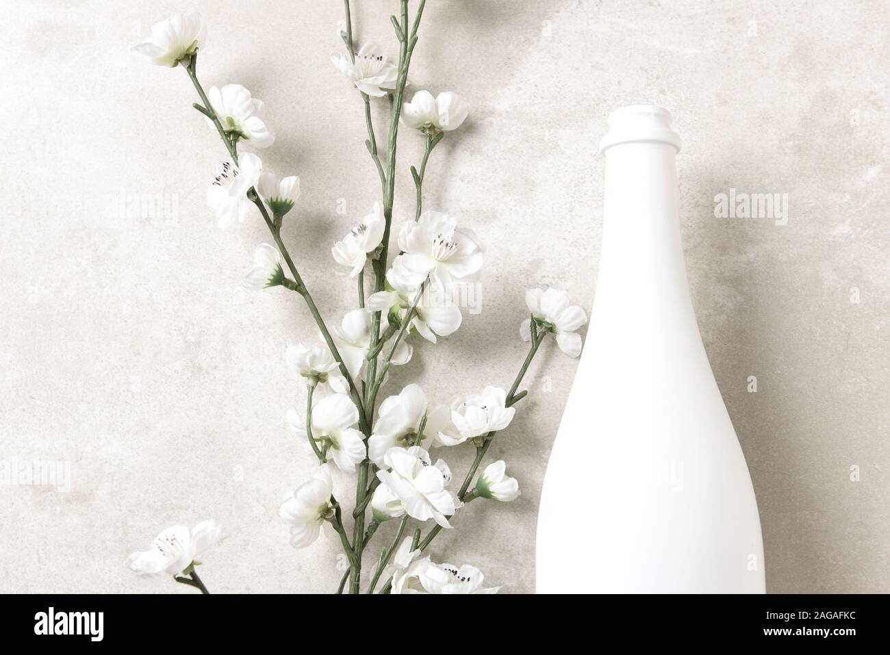 Mise à plat et bouteille de champagne blanc des fleurs sur un gris clair tacheté de table. Avec copie espace horizontal. Banque D'Images