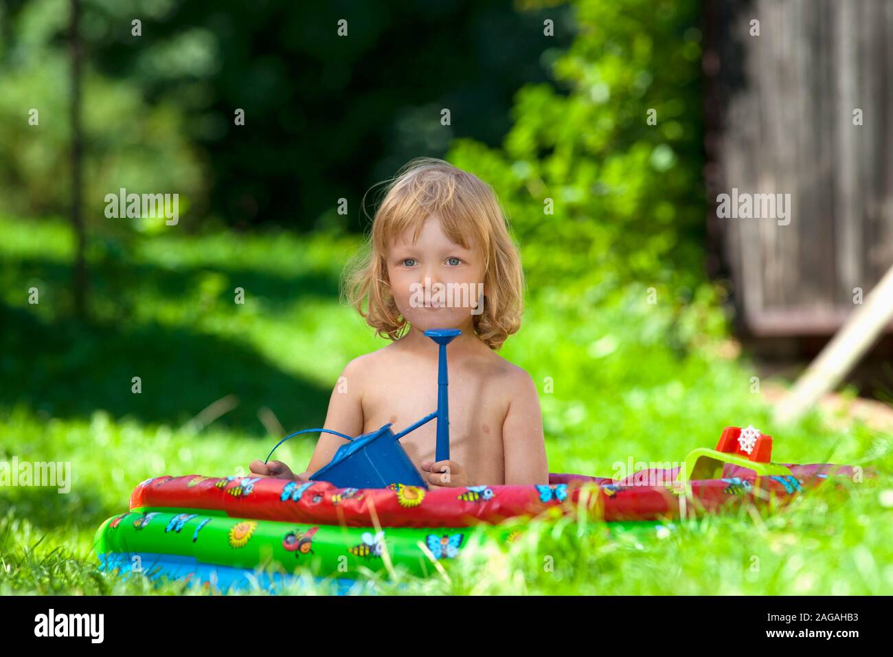 Garçon dans piscine gonflable dans le jardin Banque D'Images
