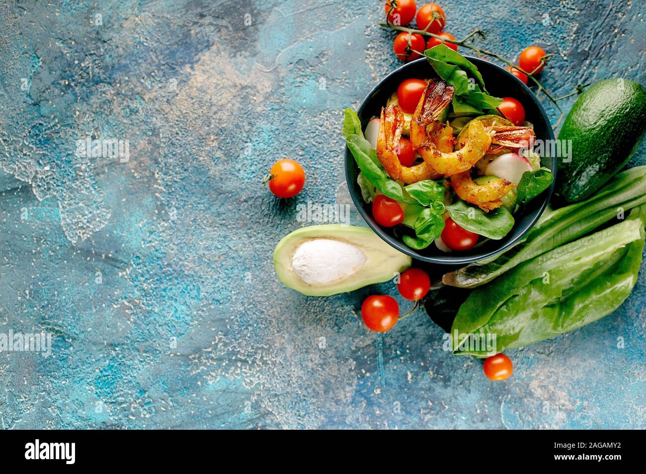 Coup horizontal avec crevettes frites salade appétissante, Avocat, tomates cerises, radis et le basilic. Savoureux et sain de fruits de mer. Copy space Banque D'Images