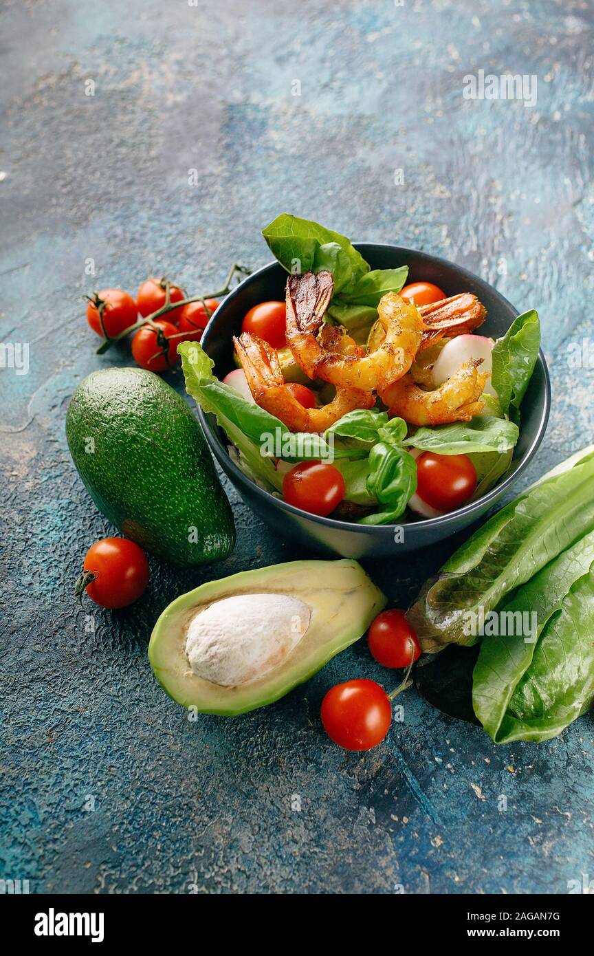 Shot verticale aux crevettes, avocat, radis et le basilic frais sur un fond de béton bleu foncé. Savoureux et sain de fruits de mer. Banque D'Images