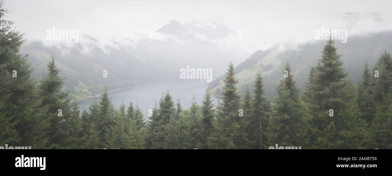 Panorama d'un lac brumeux dans les Alpes avec une montagne. Scène mystérieuse. Banque D'Images